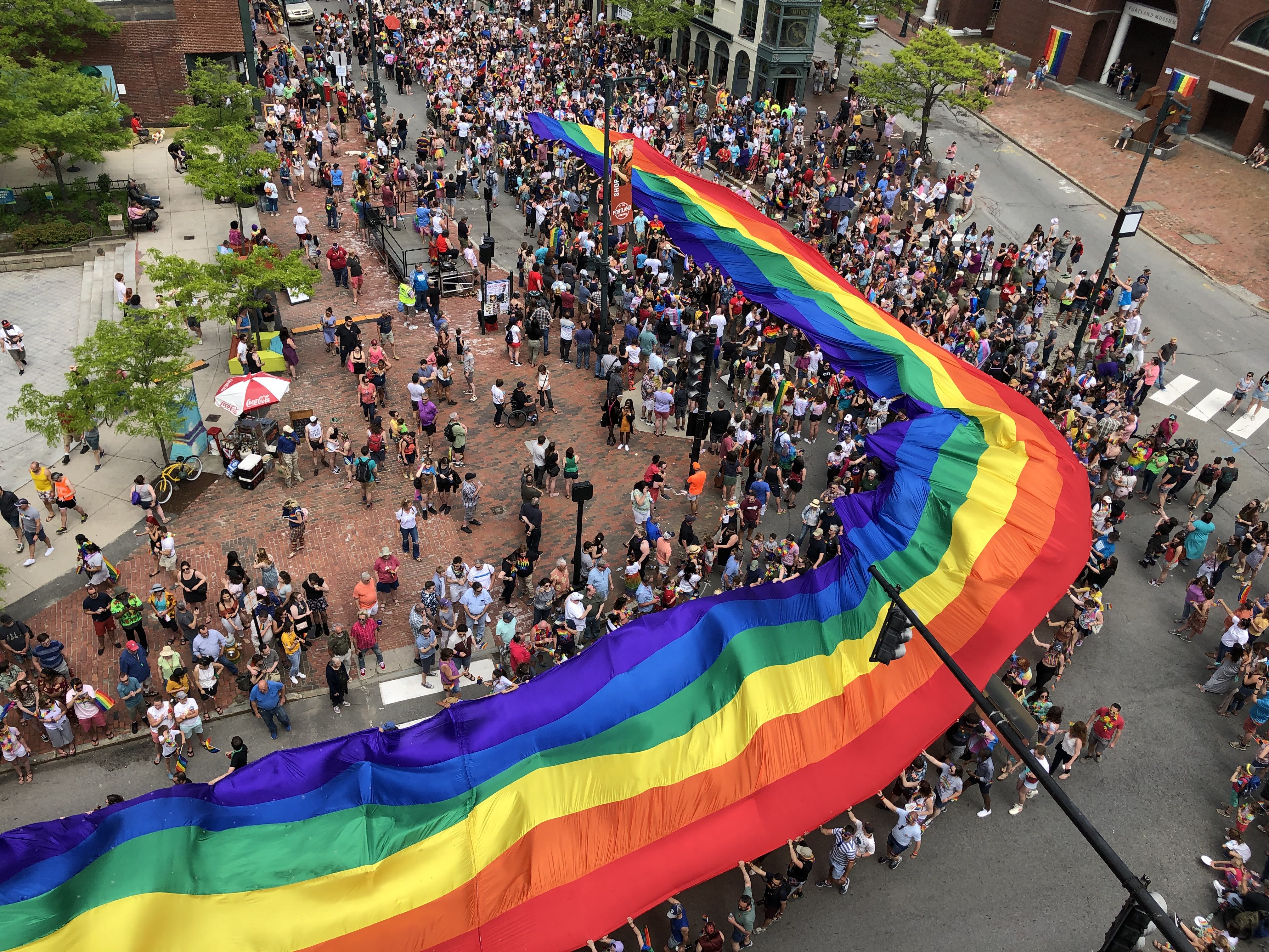 People holding up a rainbow banner in the streets of Portland ME